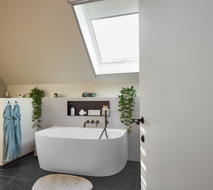 Moderne badkamerrenovatie met back-to-wall bad onder een dakraam, zwarte accenten en groene planten voor een frisse uitstraling.