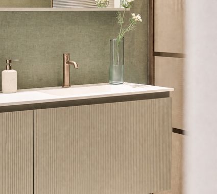 Badkamer met saliegroen badkamermeubel met brons kraanwerk en een douche geribbeld glas en bronskleurige profielen op een saliegroene muur