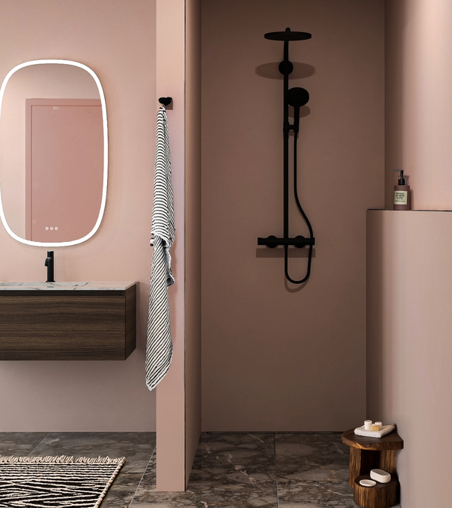 Badkamer trend met blush roze wanden, zwart sanitair, marmeren vloer en modern houten badkamermeubel met verlichte spiegel.