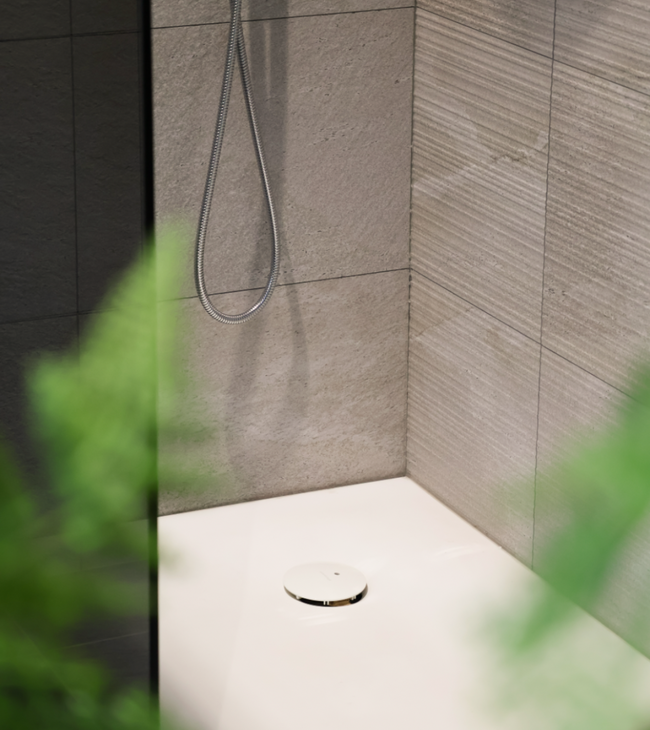 Biophilic design douche met mat witte douchebak, natuurlijke wandtegels en groene planten voor een rustgevende badkamerstijl.