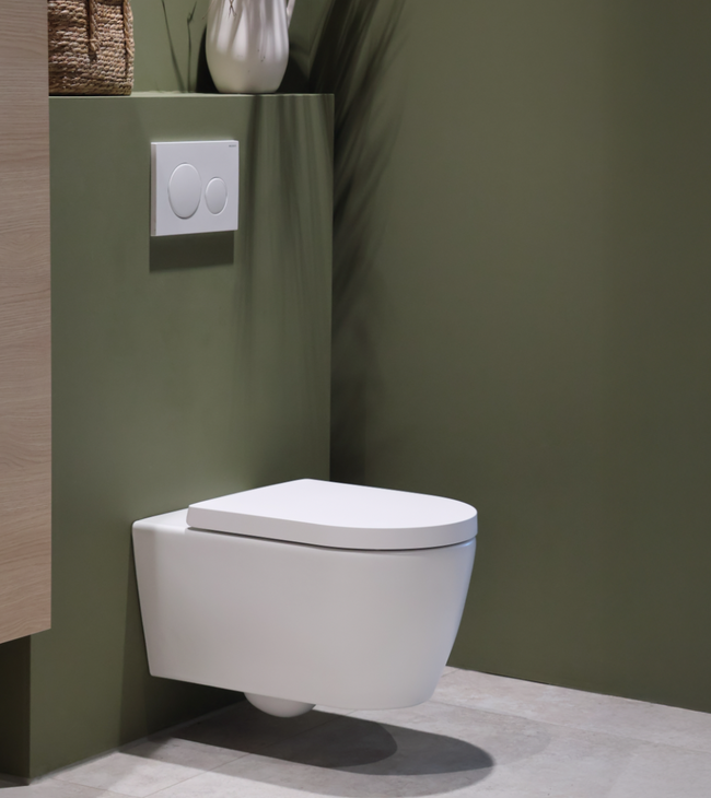 Wit hangtoilet met Geberit bedieningspaneel geplaatst tegen een stijlvolle groene muur in een Biophilic Design badkamer.