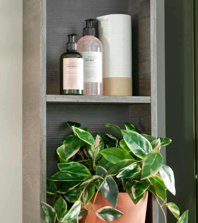 Badkamerkastje met verzorgingsproducten en groene plant in terracotta pot, perfect passend binnen een Biophilic Design interieur.