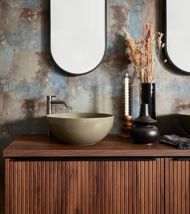 Badkamermeubel in stijl Urban Industrial met geribbeld notenhout, opbouwkom, ovale spiegel en decoratieve accessoires.