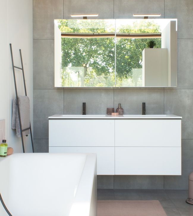 Badkamer in stijl Modern met wit badkamermeubel, zwarte kranen, grijze tegels en vrijstaand bad met zwarte handdouche.
