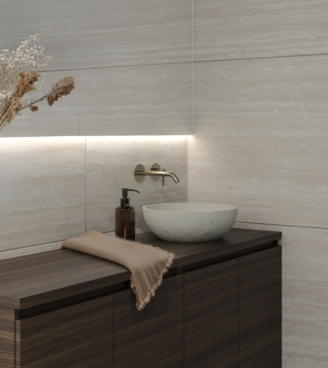 Badkamer in minimalism stijl met donker houten meubel, ronde waskom, travertin wandtegels en indirecte verlichting.