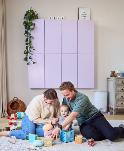 Getuigenis van jong koppel dat met hun baby speelt op de vloer, omringd door kleurrijk speelgoed in een gezellige woonkamer.