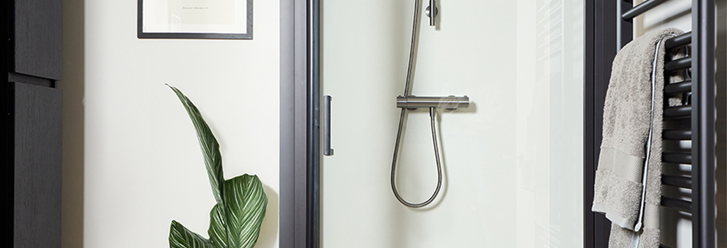 Moderne badkamer met douchedeur in zwart frame, terrazzo vloer en zwarte handdoekradiator naast de douche.